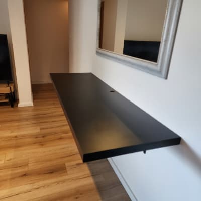 מדף עץ שחור מותקן על קיר לבן