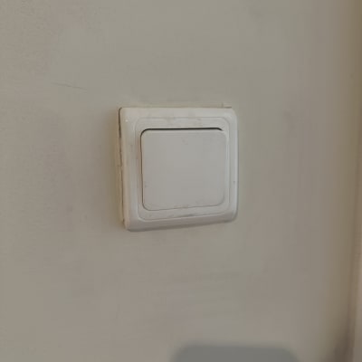 מתג חשמל לבן על קיר בהיר