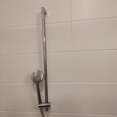 ראש מקלחת ידני על מוט מתכת בחדר אמבטיה