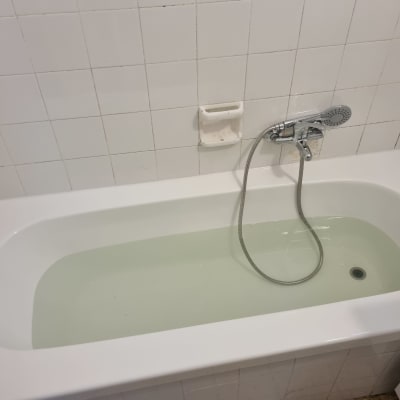 אמבטיה לבנה עם מים וברז מקלחת כסוף