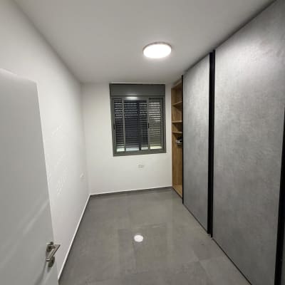 חדר ריק עם קירות לבנים ורצפת אריחים אפורה