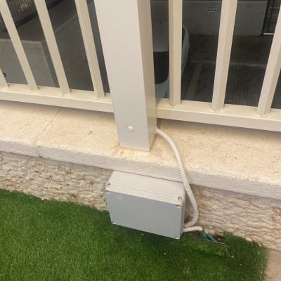 קופסת חיבורים חשמלית עם כבל ליד גדר מתכת