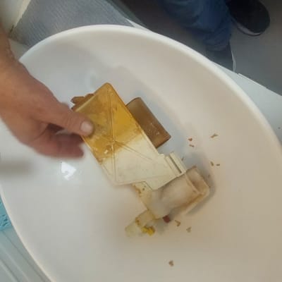 יד מחזיקה חלק פלסטיק בכיור עם כלי עבודה