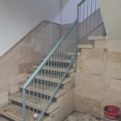 מעקה מתכת על גרם מדרגות עם קירות אבן
