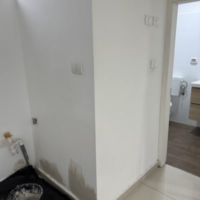 קיר צבוע חלקית עם דלי צבע וכלי עבודה