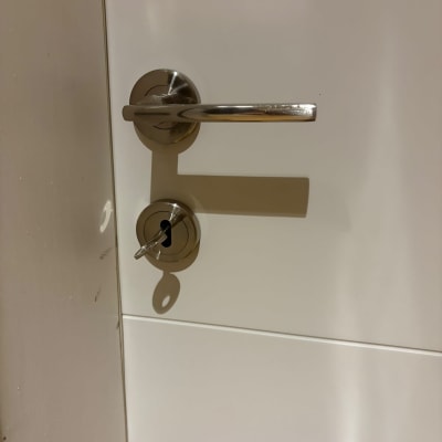 ידית ניקל וצילינדר עם מפתח מותקנים על דלת פנים לבנה