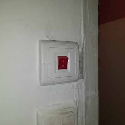 מתג חשמלי עם כפתור אדום על קיר לבן