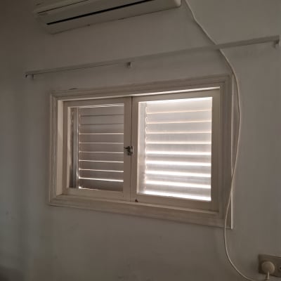 חלון עם תריסים ומזגן על הקיר
