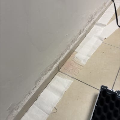 נייר סופג על רצפה ליד קיר עם סימני רטיבות