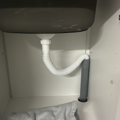 כיור עם ברז וצינור ניקוז מתחת לארון