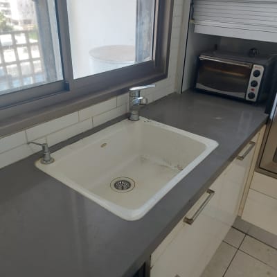 כיור מטבח מלוכלך עם ברז על משטח אפור