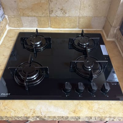 כיריים גז מזכוכית שחורה מותקנות על משטח שיש במטבח