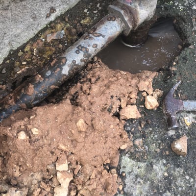 צינור מתכת חלוד עם נזילה באדמה רטובה