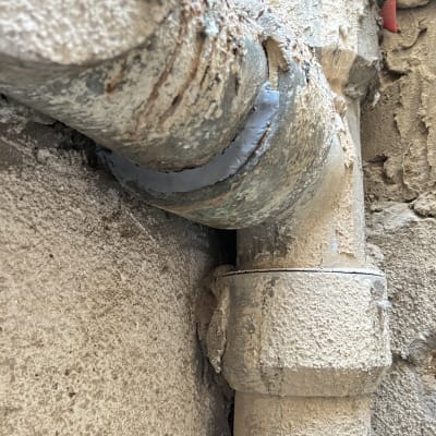 צינור מתכת עם חיבורים ותיקונים בקיר