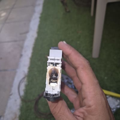 חלק חשמלי שרוף מוחזק ביד על רקע דשא