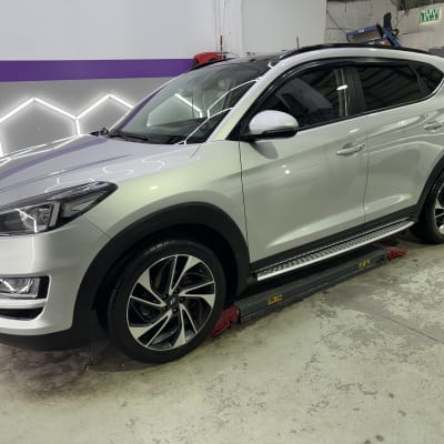 רכב לבן על מתקן הרמה בסדנת דיטיילינג