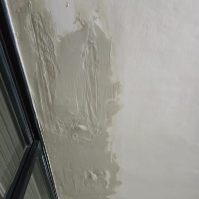 תיקון קיר עם חומר איטום ליד חלון זכוכית.