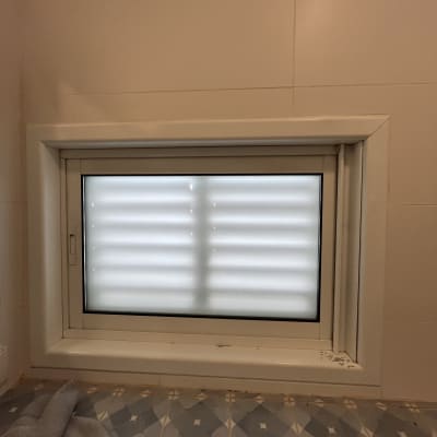חלון קטן עם תריסים סגורים על קיר אריחים