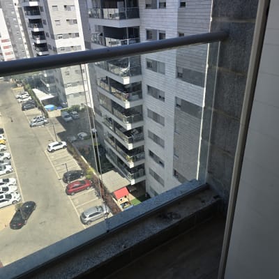 מעקה זכוכית במרפסת עם נוף לבניינים סמוכים