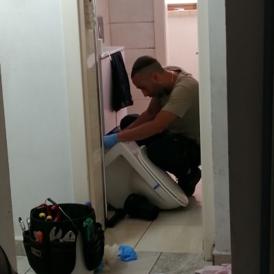 אינסטלטור עובד על אסלה עם כלים ודלי