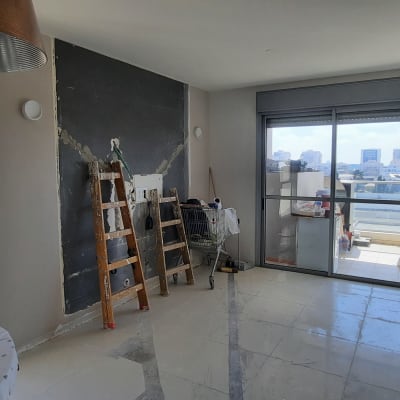 סולם עץ ליד קיר בשיפוץ עם טיח חשוף