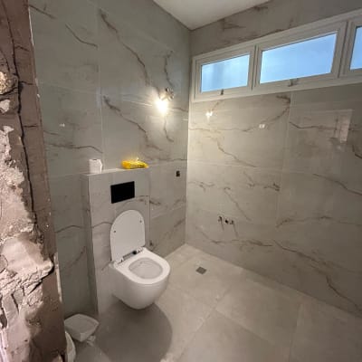 חדר אמבטיה בשיפוץ עם קירות אריחים ואסלה מותקנת