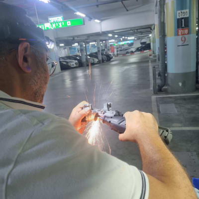 אדם עובד עם כלי חיתוך במגרש חניה