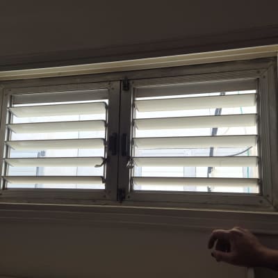 תריסים מותקנים על חלון עם יד אדם נראית בצד