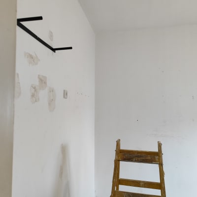 סולם עץ ליד קיר עם סימני תיקון צבע