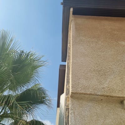 גג שטוח עם קצה מתכת כהה על קיר חיצוני