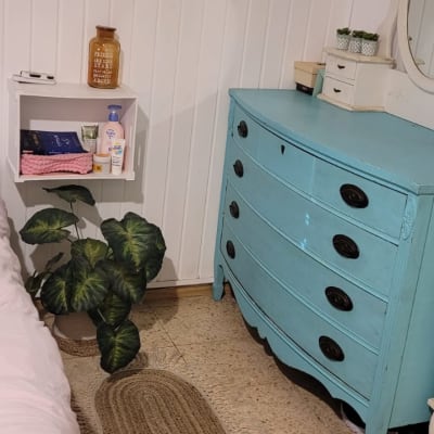 מדף עם מוצרי טיפוח ומגבות, שידה כחולה עם מראה.