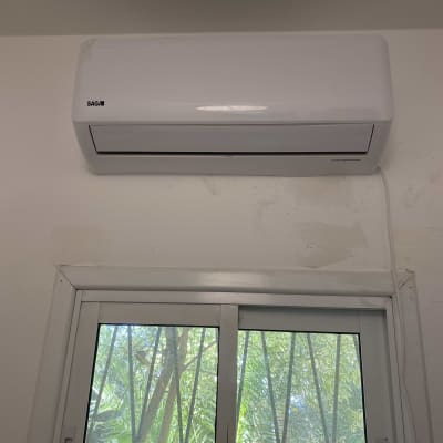 מזגן קיר לבן מותקן מעל חלון