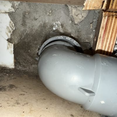 צינור פלסטיק מותקן בקיר עם סימני רטיבות