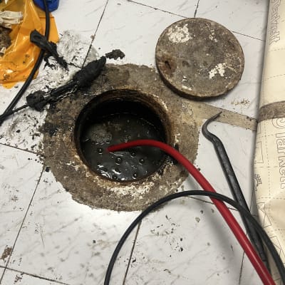 פתח ביוב עם צינור אדום וכלים מסביב