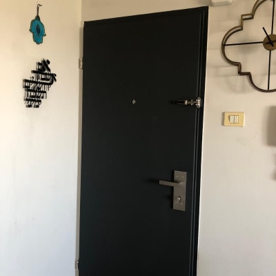 דלת שחורה עם ידית מתכת ובריח עליון