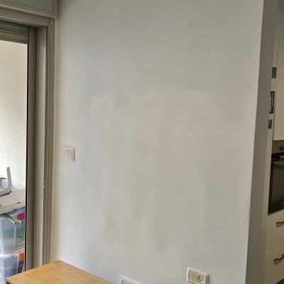 קיר צבוע עם שידה מעץ ליד חלון