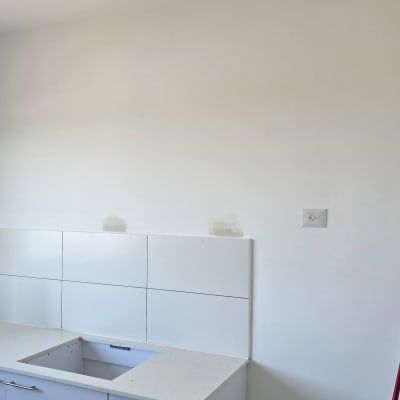 קיר צבוע עם ארונות מטבח וכיסא ירוק