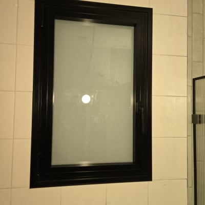 חלון אלומיניום עם מסגרת שחורה על קיר אריחים