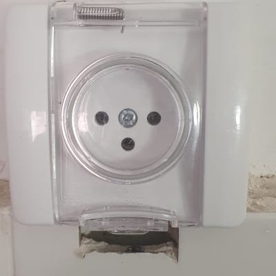 שקע חשמלי עם כיסוי שקוף על קיר לבן