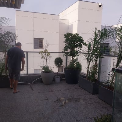 אדם משקה צמחים במרפסת עם עציצים גדולים