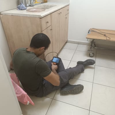 אדם יושב על הרצפה עם מכשיר אלקטרוני ביד