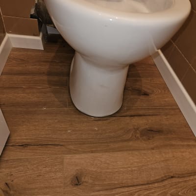 אסלה מותקנת על רצפת עץ בחדר אמבטיה