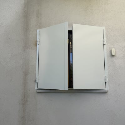 תריסים לבנים פתוחים על קיר חיצוני