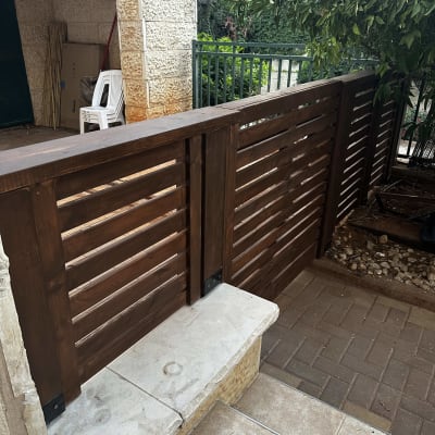 גדר עץ חומה ליד שביל מרוצף ועץ ירוק