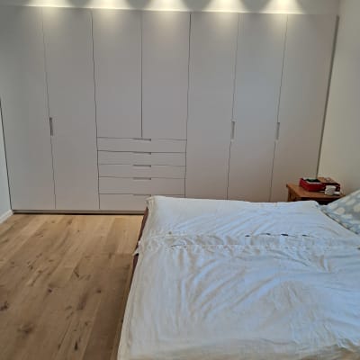 ארון בגדים לבן עם דלתות ומגירות בחדר שינה