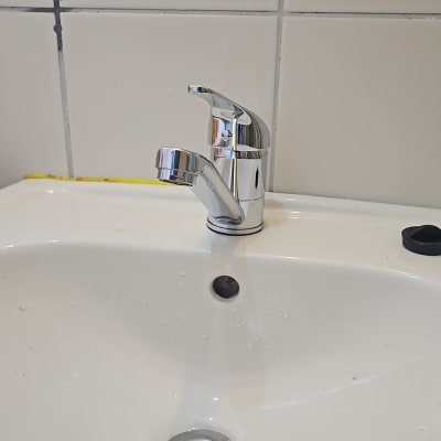 ברז כרום מותקן על כיור לבן עם חור ניקוז