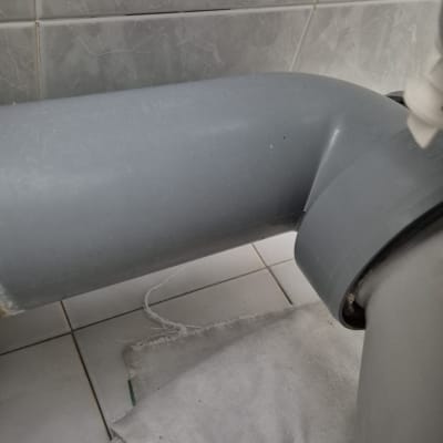 צינור אפור עם חיבורי אינסטלציה על רצפת קרמיקה