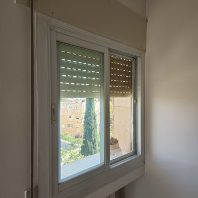 תריסים סגורים על חלון פנימי עם נוף חיצוני