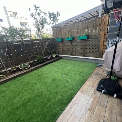 גינה עם דשא מלאכותי וצמחים בעציצים תלויים