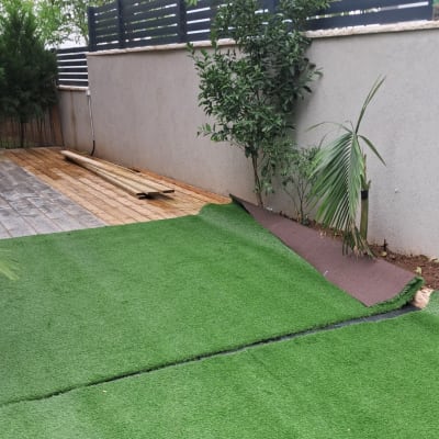 דשא סינתטי מונח ליד עצים וקרקע חשופה